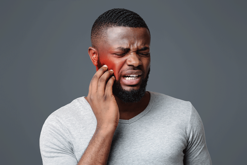 Man in pain touching his cheek, white studio background, tooth disease concept. Grey background, red cheek